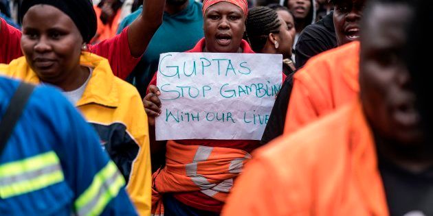 Employees and contractors of the Optimum Coal Mine in Hendrina, owned by the controversial Gupta family, demonstrate with a placard reading 'Guptas - stop gambling with our lives' in front of the gates of the mine in Hendrina, South Africa, on February 22, 2018.