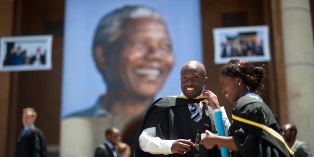 Students celebrate their graduation ceremony on the steps of Cape Town University where a giant picture of Nelson Mandela hangs down on December 13 2013, in Cape Town.