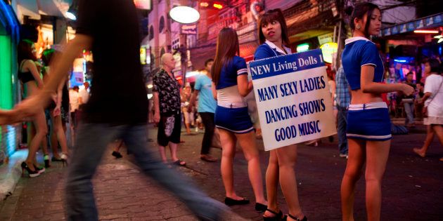 Young Thai girls in cosplay uniforms stand outside the brothels of Pattaya city.