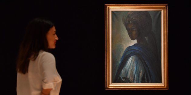 An employee poses with a work of art by Nigerian painter and sculptor Ben Enwonwu entitled Tutu.