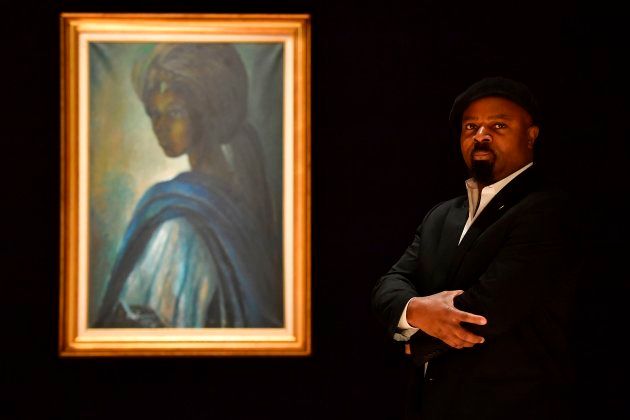 Nigerian author Ben Okri poses with a work of art by Nigerian painter and sculptor Ben Enwonwu entitled 'Tutu'.