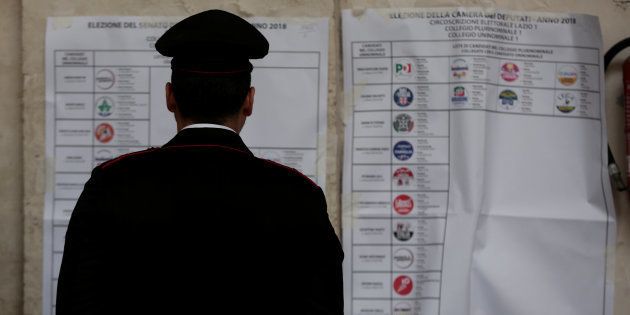 An Italian policeman looks at an electoral poster at a polling station in Rome, Italy March 4, 2018.