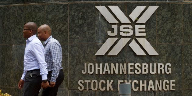 Workers pass a sign outside the headquarters of the Johannesburg Stock Exchange (JSE) in the Sandton district of Johannesburg, South Africa, on Thursday, Dec. 19, 2013.