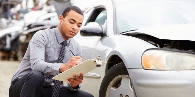 Loss adjuster inspecting car involved in accident.