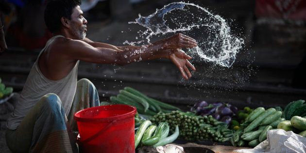 A vendor splashes water as he sells vegetable next to a railway track in Dhaka May 29, 2014.