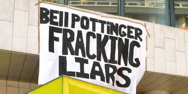 A group of commuters stand and take pictures of anti-fracking demonstrators, as they sit with their hands super-glued to each other at the offices of Bell Pottinger in central London.