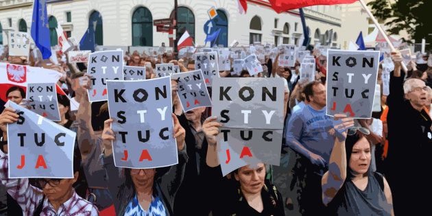 Demonstrators in Poland hold posters reading