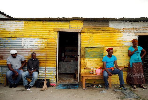Members of a mining community sit outside a shack in Nkaneng township, Marikana's informal settlement, in Rustenburg, South Africa, April 1, 2014.
