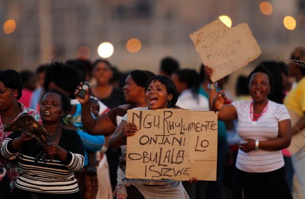 Women carry placards as they chant slogans to protest against the killing of miners by the South African police on Thursday, outside a South African mine in Rustenburg, 100 km (62 miles) northwest of Johannesburg, August 17, 2012. REUTERS/Siphiwe Sibeko