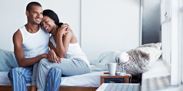 Shot of a happy young couple sitting on their bed