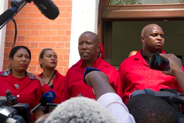 Economic Freedom Fighters (EFF) party leader Julius Malema (C) and fellow EFF members of the Parliament answer journalists' questions as they walk out of the National Assembly, on February 16, 2018 in Cape Town. (Photo credit should read NASIEF MANIE/AFP/Getty Images)