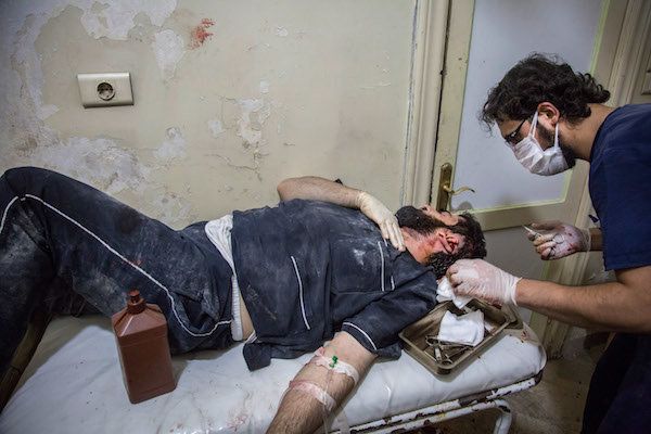 A doctor stitches the ear of a man injured in airstrikes on Bab Al Nayrab district, east Aleppo.