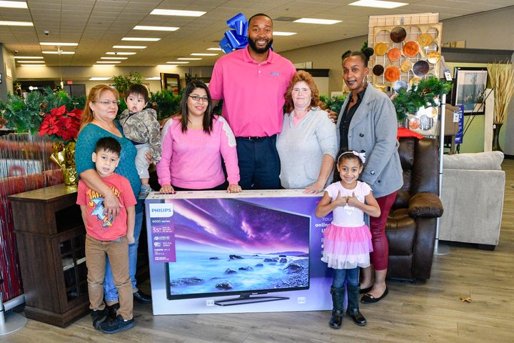 IMAGE DISTRIBUTED FOR AARON'S, INC. Aaron's regional manager Tyrone Washington, center, surprised loyal customers (L - R) Aurora Moreno, her daughter and grandkids, Melissa Neese, and Salina Arnold with free 55 Phillips Smart 4K UHD LED TVs at an Aaron's store on Monday, Nov. 21, 2016, in Atlanta, Ga.