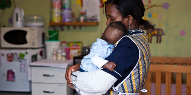 A young baby suffering from Fetal Alcohol Syndrome in the arms of a child minder.