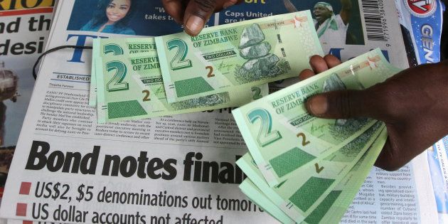 A street vendor poses with new bond notes in the capital Harare, Zimbabwe, November 28, 2016. REUTERS/Philimon Bulawayo