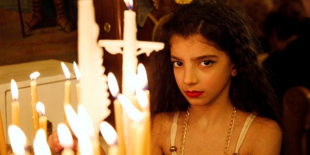 A girl stands near candles inside Al-Saleeb church during Palm Sunday in Damascus, Syria on April 9, 2017.