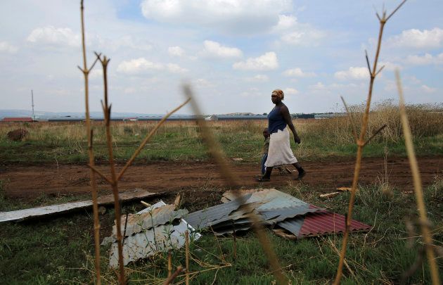 A mother and child walk past corrugated iron left by residents who intended to build an informal settlement at an open land in Nellmapius township, 20 km (12 miles) east of Pretoria, November 13, 2014. REUTERS/Siphiwe Sibeko