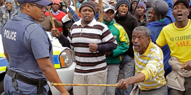 A South African policeman, left, provide security as farm workers demonstrate due to low wages in the town of Grabouw, South Africa, Wednesday, Jan 9, 2013.