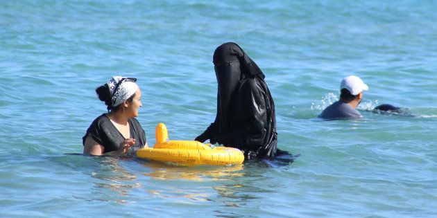 A woman wearing a niqab (C) cools off on the beach in Bizerte, Tunisia, July 21, 2016.