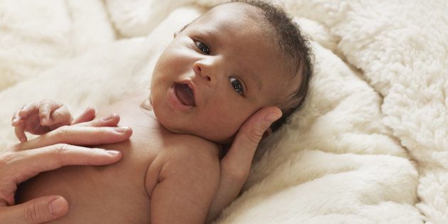 Close up of mother's hands caressing baby on bed