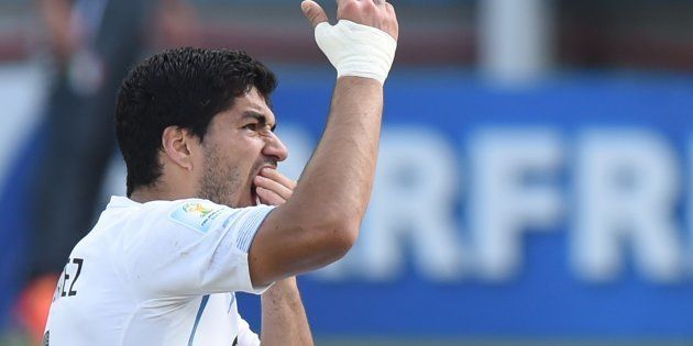 Uruguay forward Luis Suarez puts his hand to his mouth after clashing with Italy's defender Giorgio Chiellini during a Group D football match between Italy and Uruguay at the Dunas Arena in Natal during the 2014 FIFA World Cup on June 24, 2014.