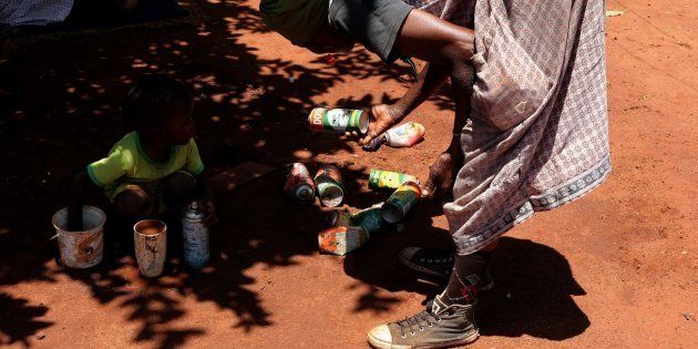 A woman picks up empty Doom containers in the open space where Lethabo Rabalago sprays people with Doom (insecticide) as part of healing on November 22, 2016 in Limpopo, South Africa.