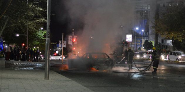 Firefighters extinguish a car that police said was set on fire during a confrontation between Uber and meter taxi drivers in Sandton, South Africa, September 7, 2017.