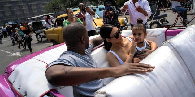 American reality-show star Kim Kardashian wipes her daughter's face, North West, as she rides in a classic American car with her husband, rap singer Kanye West in Havana, Cuba, Thursday, May 5, 2016.