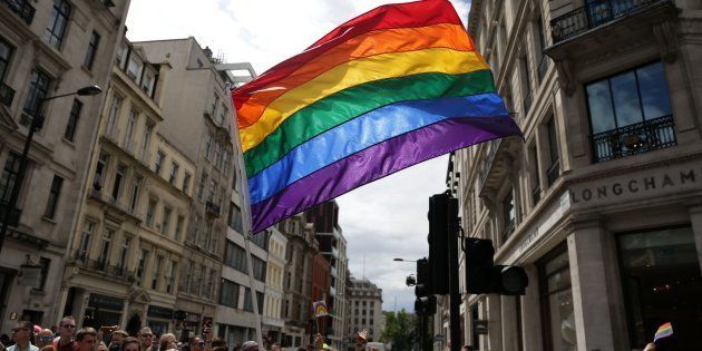 A rainbow flag is held aloft as the Pride in London parade makes its way through the streets of central, London.