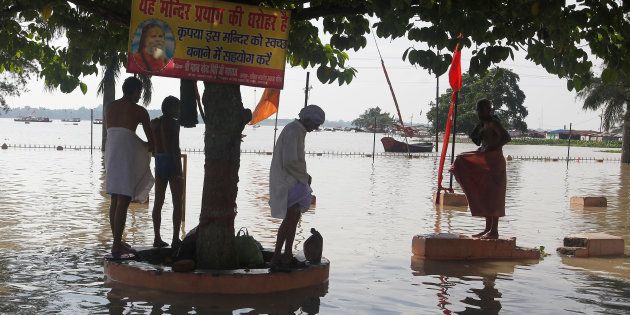 People change clothes after bathing from a tap at the flooded banks of river Ganga after heavy rains in Allahabad, India, August 9, 2016.