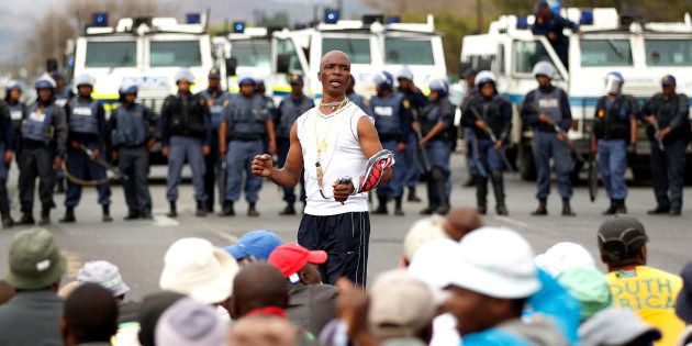 A protester sings as police officers stand guard to prevent marchers from proceeding, in Rustenburg, South Africa's North West Province 16 September 2012.