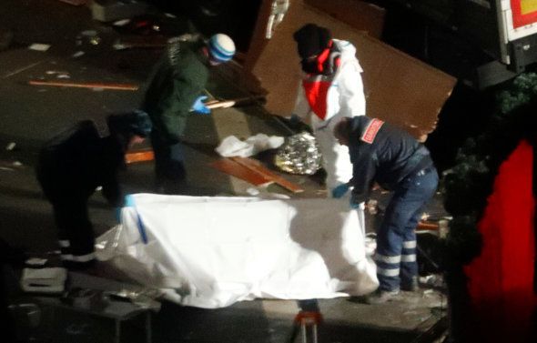 Police investigators cover a victim after a truck ploughed through a crowd at a Christmas market on Breitscheidplatz square near the fashionable Kurfuerstendamm avenue in the west of Berlin, Germany, December 20, 2016.