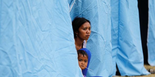 A woman and child sit in a tent at a temporary evacuation center for people living near Mount Agung, a volcano on the highest alert level, outside a sports arena in Klungkung, on the resort island of Bali, Indonesia, September 24, 2017.