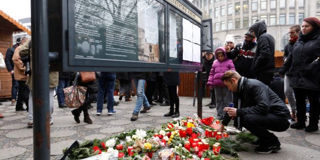 People gather to lay down flowers outside the Gedaechniskirche near the area where a truck which ploughed into a crowded Christmas market in the German capital last night in Berlin.