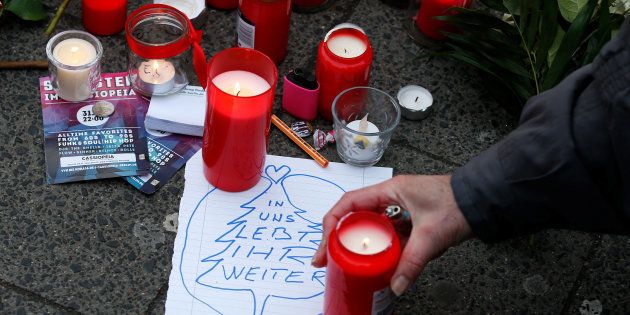 A man lights a candle near the scene where a truck ploughed into a crowded Christmas market in the German capital last night in Berlin, Germany, December 20, 2016.The sticker reads "In us you continue living - Berliner". REUTERS/Fabrizio Bensch