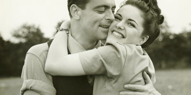 Young couple embracing in field, man kissing woman, (B&W)