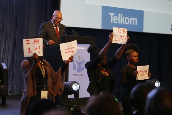 Four young women hold posters during President Jacob Zumas speech at the IEC briefing after the 2016 local government elections on August 06, 2016 in Pretoria, South Africa. Four women staged an anti-rape silent protest directed at Zuma while he delivered his speech during the announcement of the final election results.