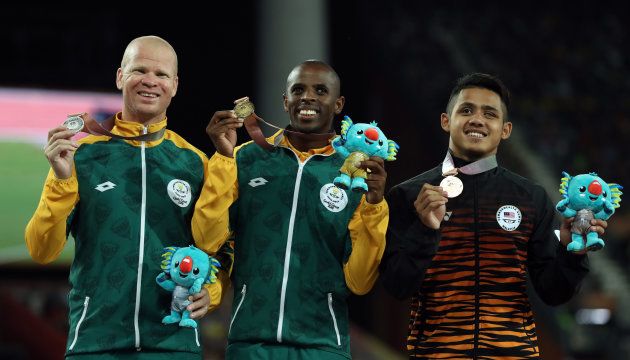 Athletics - Gold Coast 2018 Commonwealth Games - Men's T12 100m - Medal Ceremony - Carrara Stadium - Gold Coast, Australia - April 12, 2018. Gold medalist Ndodomzi Ntutu of South Africa, silver medalist Hilton Langenhoven of South Africa and bronze medalist Muhamad Afiq Mohamad Ali Hanafiah of Malaysia on the podium.