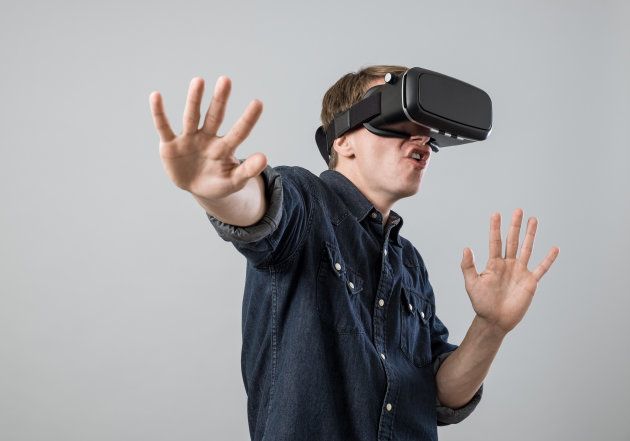 Man using virtual reality goggles on grey background