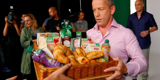 Tennis star Andre Agassi (R) of the U.S. looks on as Hungarian fitness guru Norbert Schobert is handed a basket of bakery products during a photo shoot for an advertisement campaign in Budapest, September 11, 2014. Schobert, a former Hungarian policeman who built up a chain of 112 stores selling his low-carbohydrate food, has signed up Agassi to be the face of an expansion into Europe, which he plans to finance with an $8.3 million share offer.