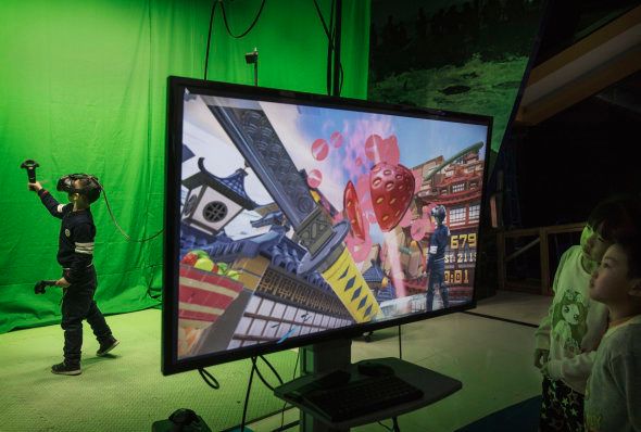 A Chinese boy, left, wears virtual reality glasses (VR) as he plays a game at the Wantong VR Park, which claims to be China's largest, on November 27, 2016 in Beijing, China.