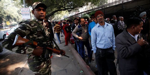 People queue outside the Reserve Bank of India to exchange their old high denomination bank notes as a security official stands guard, in New Delhi, India, on December 30. It's the final day for changing the notes.