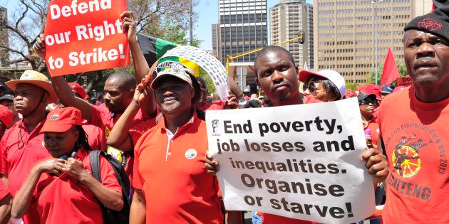 People carry placards during a COSATU march in Braamfontein on October 7, 2016 in Johannesburg.