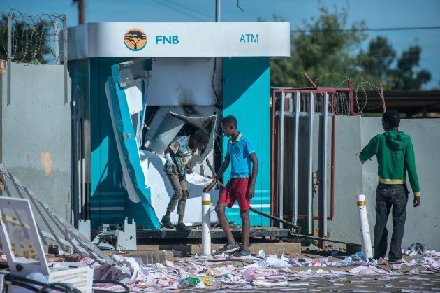 Children play around a vandalised ATM in North West Province on April 20, 2018, as protest continued for a second day in province capital of Mahikeng.
