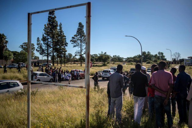 Bystanders and foreign nationals stand at a crossroad on April 20, 2018, as protest continued for a second day in the North West province capital of Mahikeng.