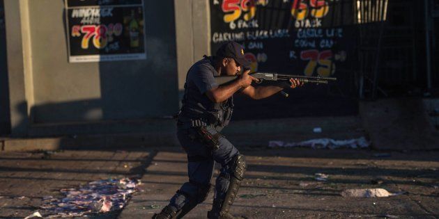 A South African riot police officer fires rubber bullets to prevent looting in North West on April 20, 2018, as protests continued for a second day in provincial capital of Mahikeng.
