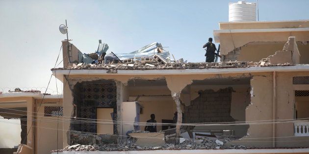 Somali policemen inspect a destroyed hotel building after a suicide attack at a checkpoint outside the main base of an African Union peacekeeping force in the Somali capital Mogadishu, January 2, 2017.