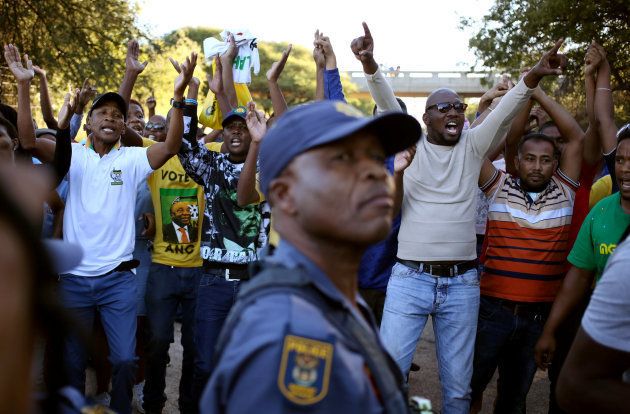 A police officer looks on as protesters chant slogans during protests in Mahikeng, in North West. April 20, 2018.