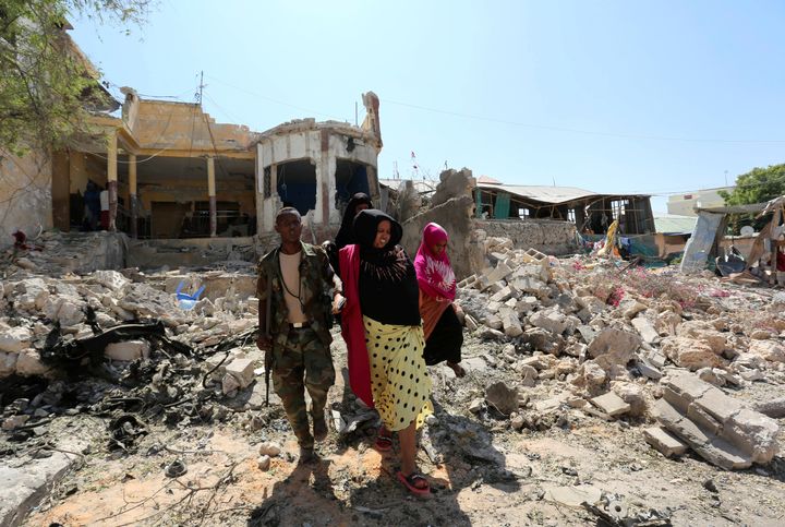 A Somali soldier assists a woman injured in the explosion to walk through rubble after a suicide attack at a checkpoint outside the main base of an African Union peacekeeping force in the Somali capital Mogadishu, January 2, 2017.