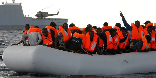 An overcrowded raft carrying African migrants is seen in front of an Italian Navy vessel in the Mediterranean Sea, as lifeguards from the Spanish NGO Proactiva Open Arms rescue all 112 on board on January 2, 2017.